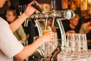 A photo of a bartender pouring a beer from a tap