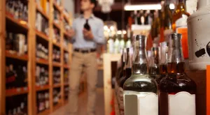 consumer evaluating liquor bottles in background and bottles with blank labels in focus at the forefront